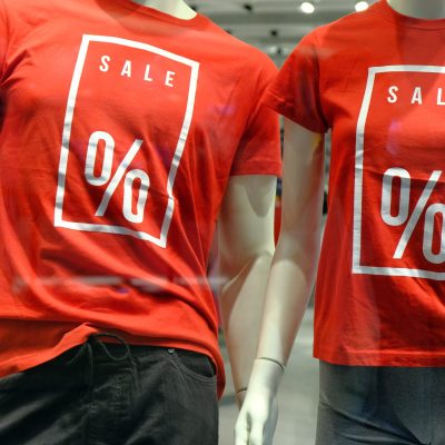 Window Of Boutique With Two Mannequins In T Shirts With Signs Ad
